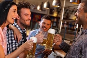 14821368-Happy-young-friends-drinking-beer-having-fun-in-pub-smiling--Stock-Photo